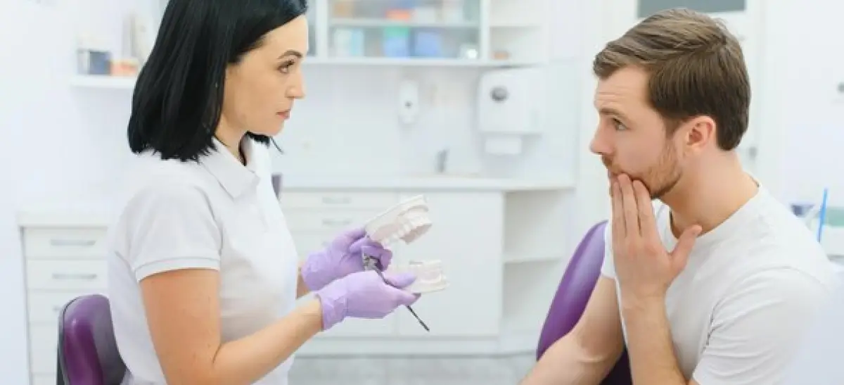 Dentista explicando sintomas de infecção no implante dentário para paciente