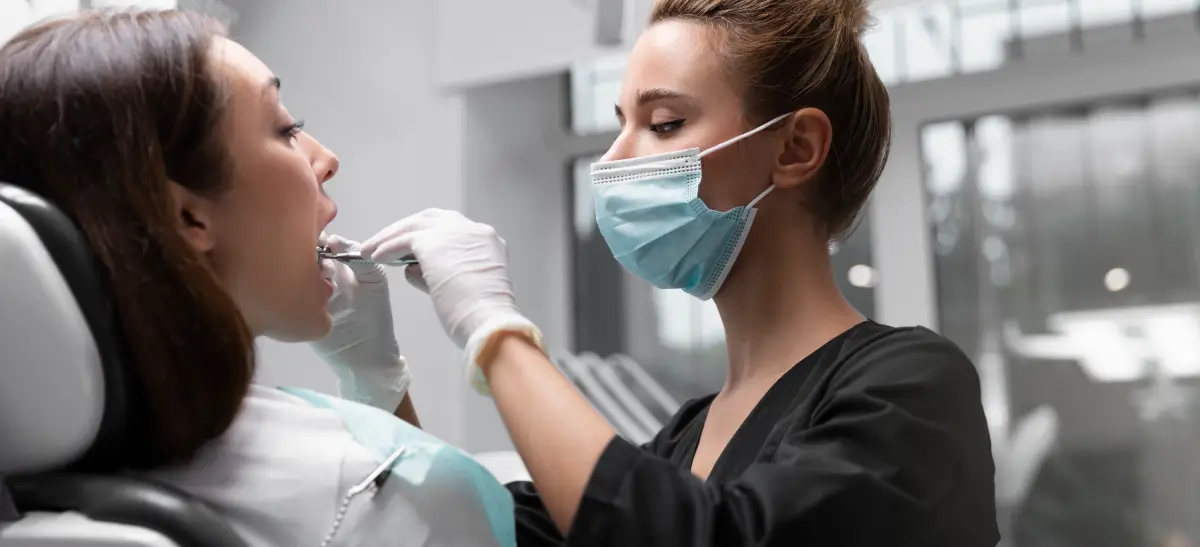 Dentista realizando o procedimento de raspagem nos dentes em paciente