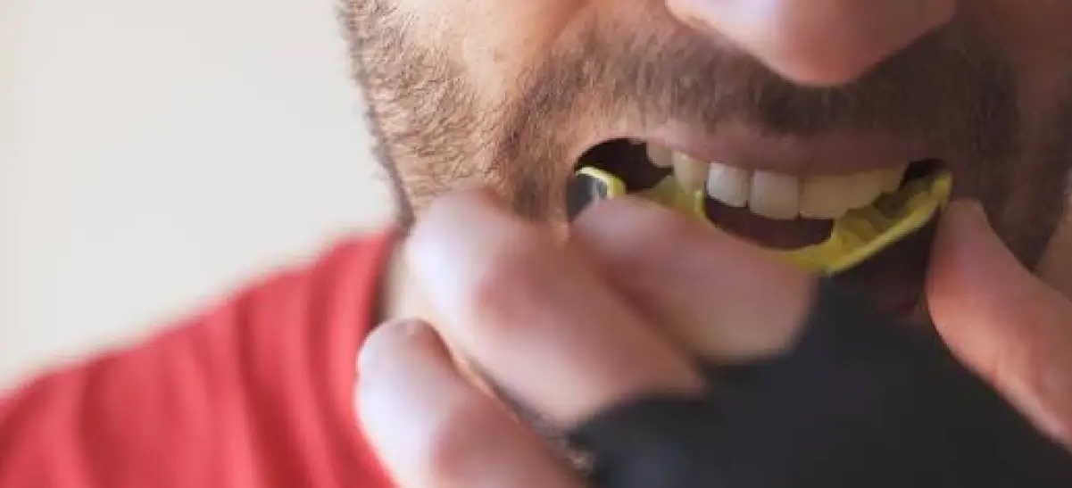 Homem colocando protetor bucal para proteger os dentes durante atividade esportiva
