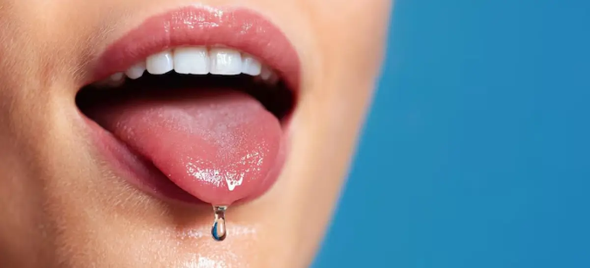Close-up de boca com gota de saliva na língua, ilustrando excesso de salivação